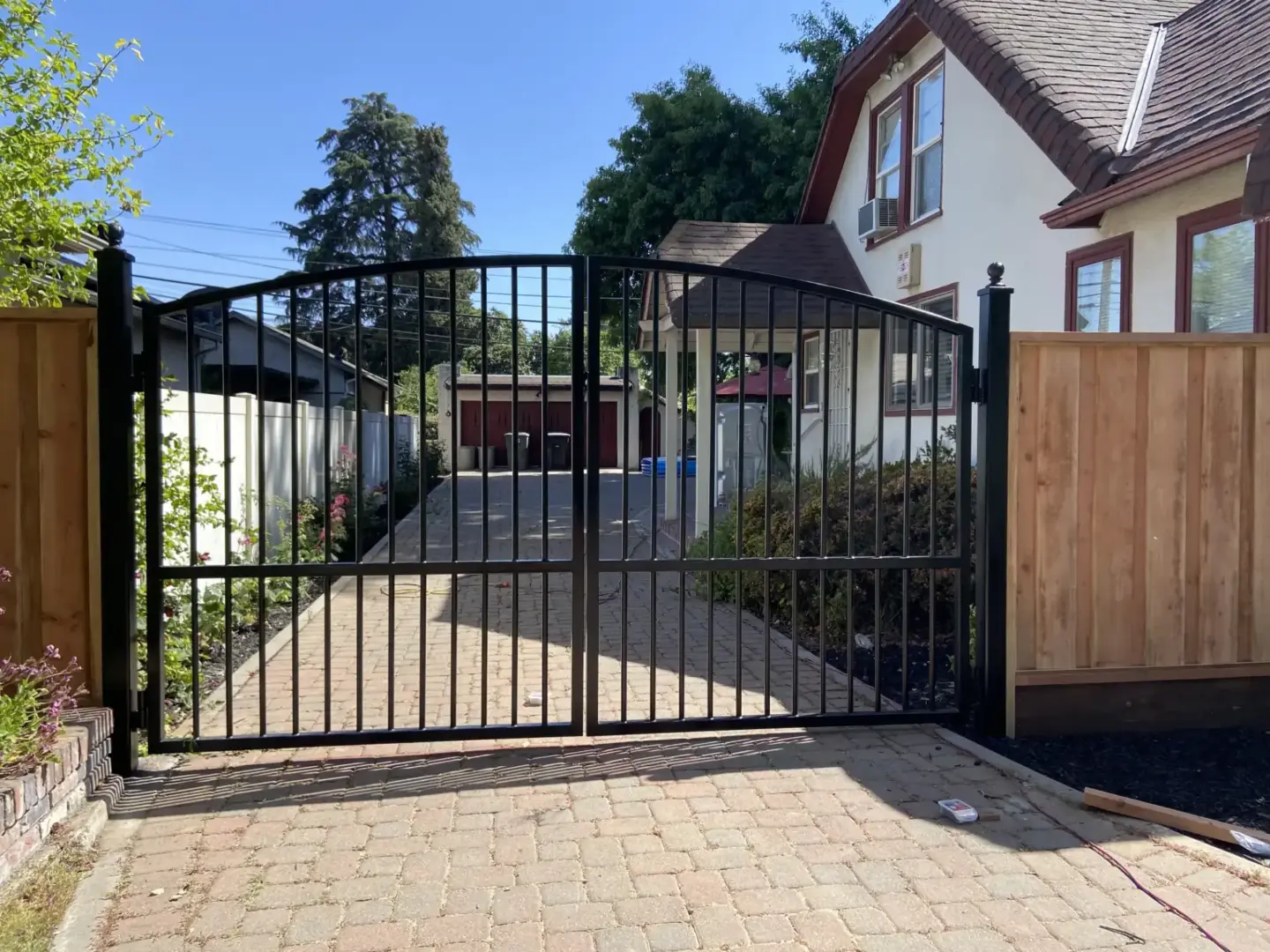 Black metal residential gate installation with wooden fence in charleston sc