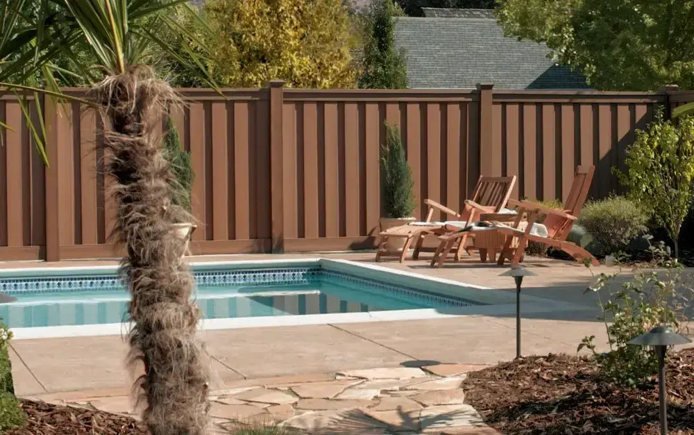 Residential pool fence with chairs featuring grass and trees on the background in charleston sc
