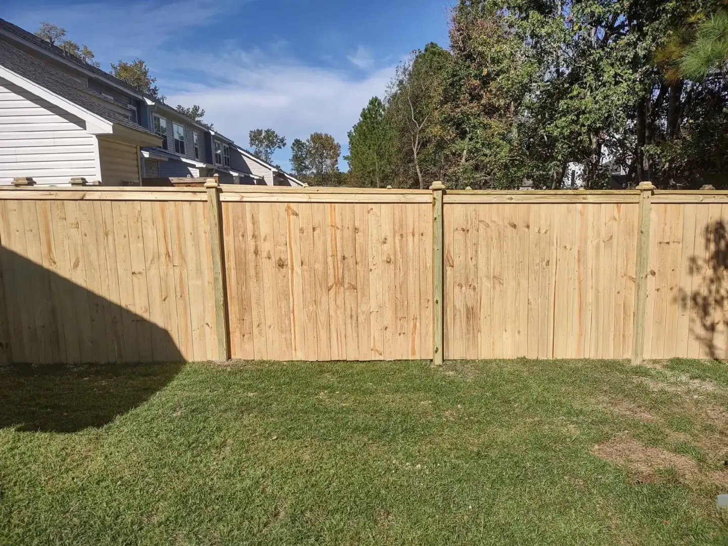Wooden privacy fence featuring trees and grass on the background in charleston sc